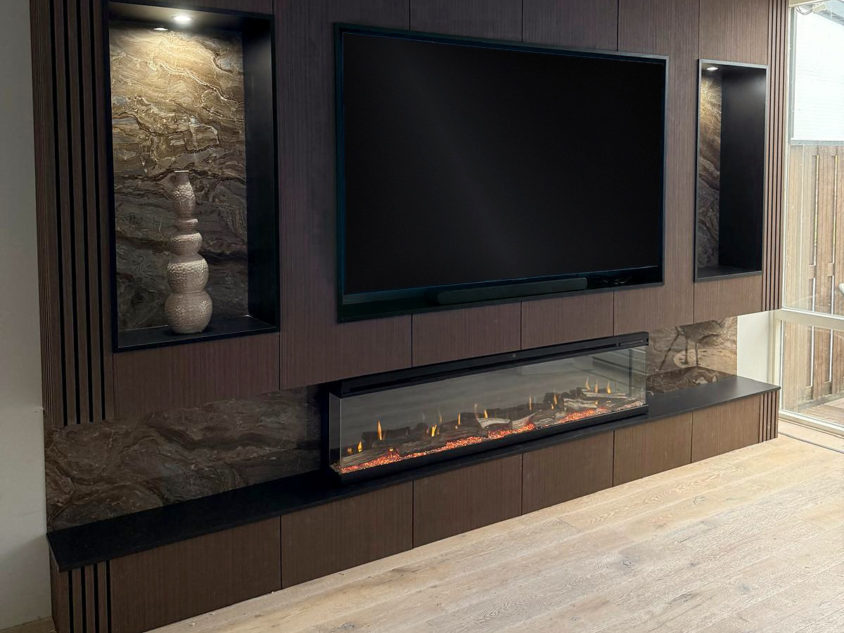 Cinewall in donker notenhout met een verlichte natuurstenen nis, verzonken televisie en een brandende lijnhaard