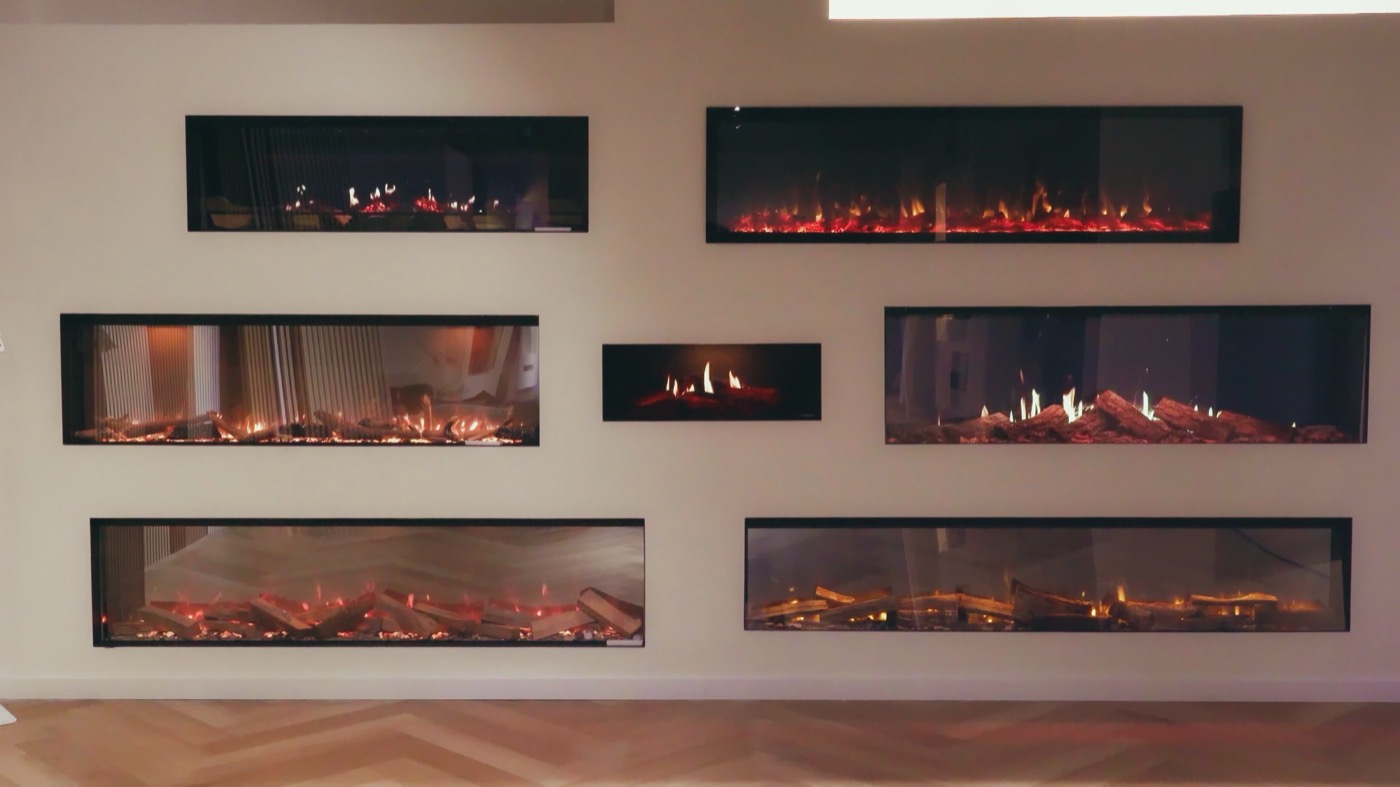 Wand met meerdere brandende elektrische sfeerhaarden in de showroom van Ember Fires in Zeewolde